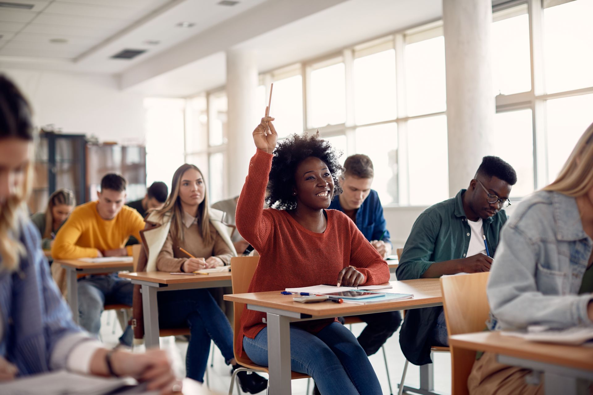 Student raising hand in a classroom full of attentive students