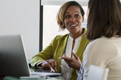 Two women discussing careers at a desk with a laptop
