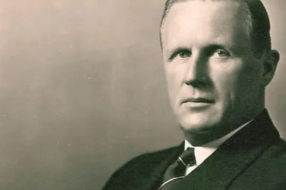 Portrait en noir et blanc d’un homme sérieux en costume et cravate, face à l’objectif