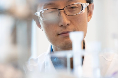 Scientifique en blouse et lunettes observant attentivement du matériel de laboratoire pendant une expérience